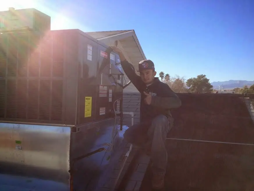HVAC technician performing AC Tune-Up on a rooftop unit in Wesley Hills